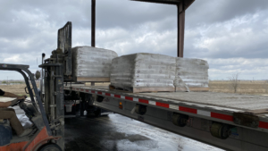 Bags of PCS product shrink wrapped on pallets on flat bed truck